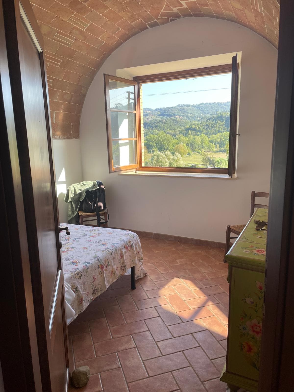 Bedroom viewed through a doorway with a brick vault and window