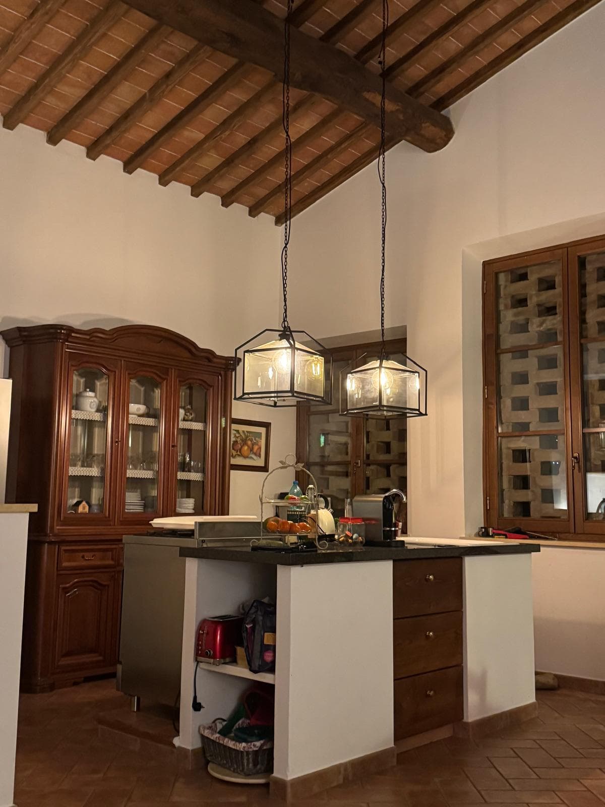Kitchen island with pendant lanterns and an antique vitrine