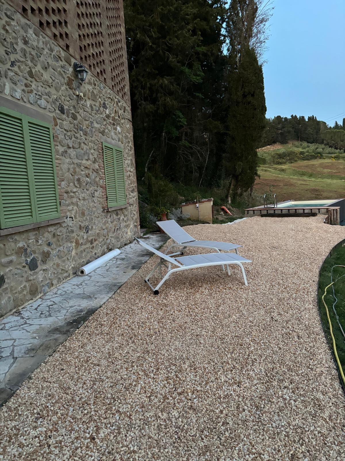 Sun loungers beside the villa stone wall with the pool beyond