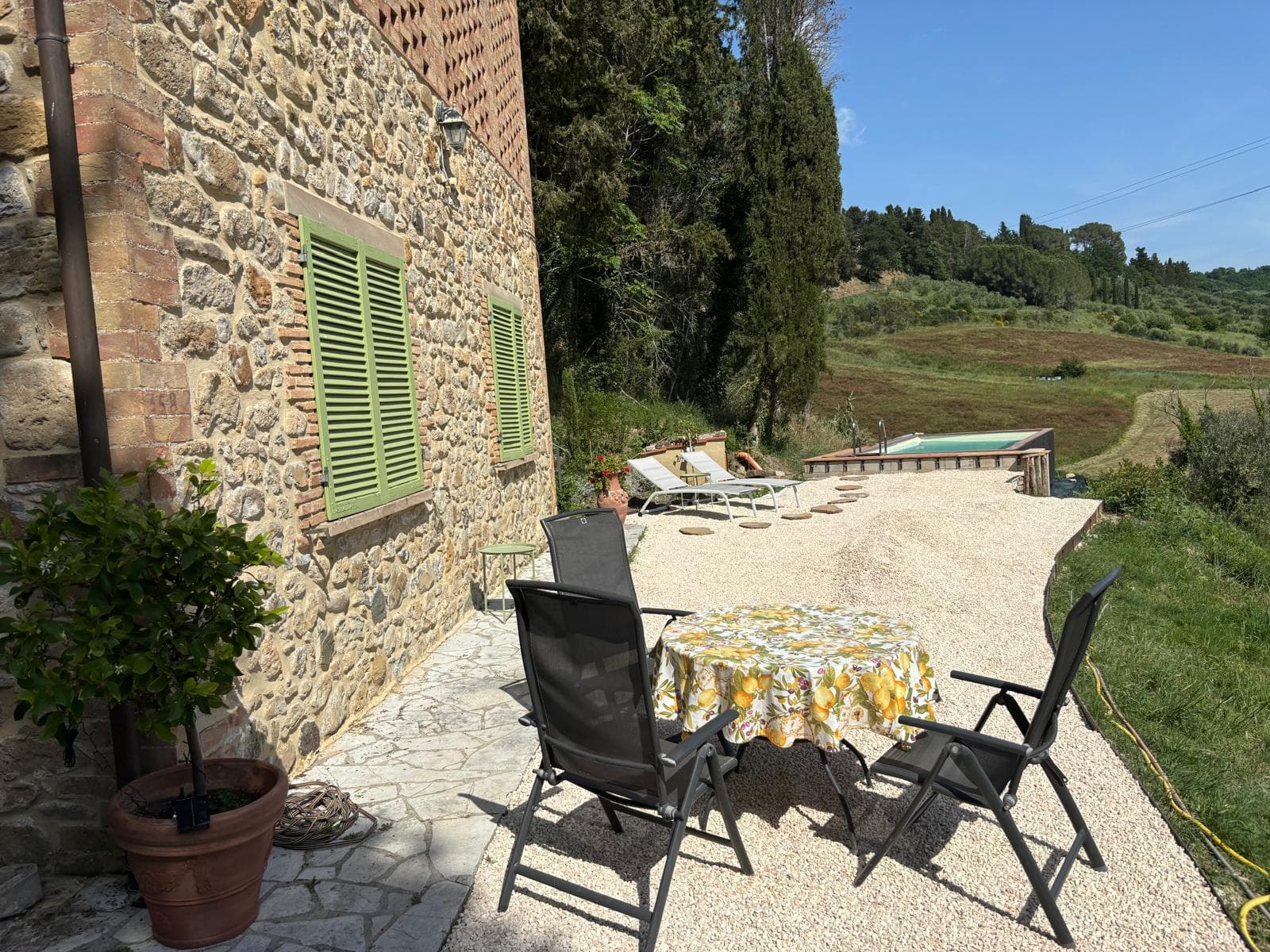Terrace dining table against the stone villa with a pool view